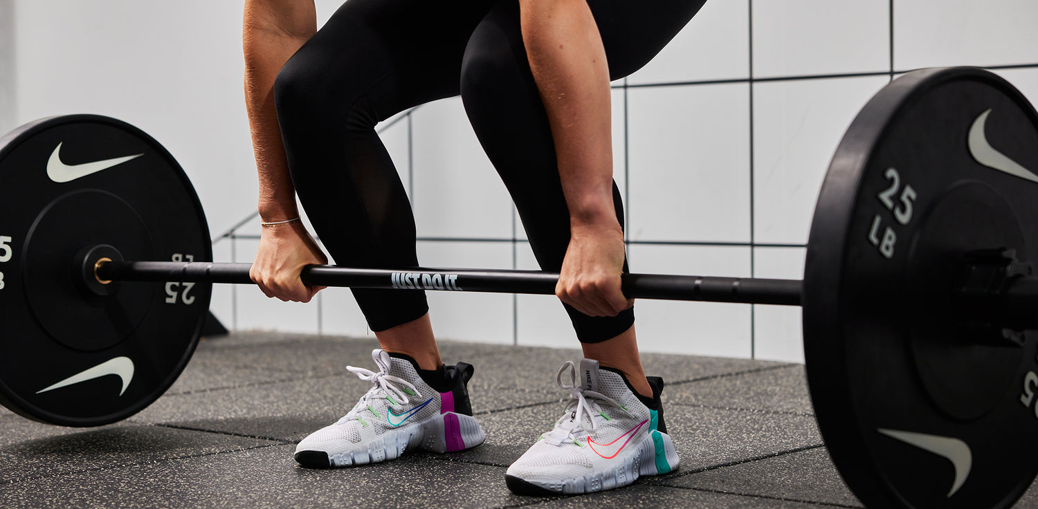 Athlete lifting the Nike coated Premium Barbell 15kg with Nike Rubber Bumper Plates 25 LB
