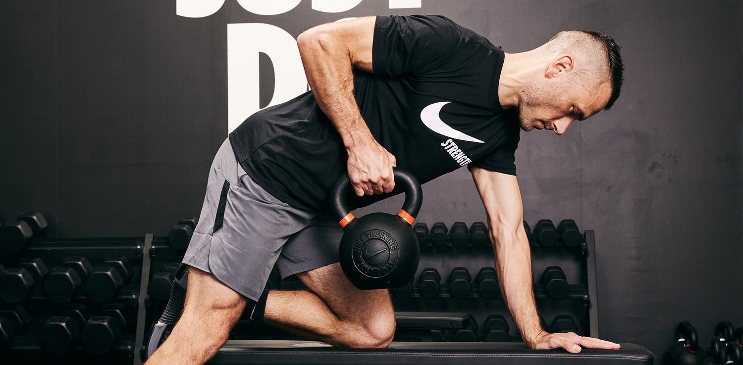 Male athlete rowing the Nike Kettlebell 62 LB using the Nike Roller Bench