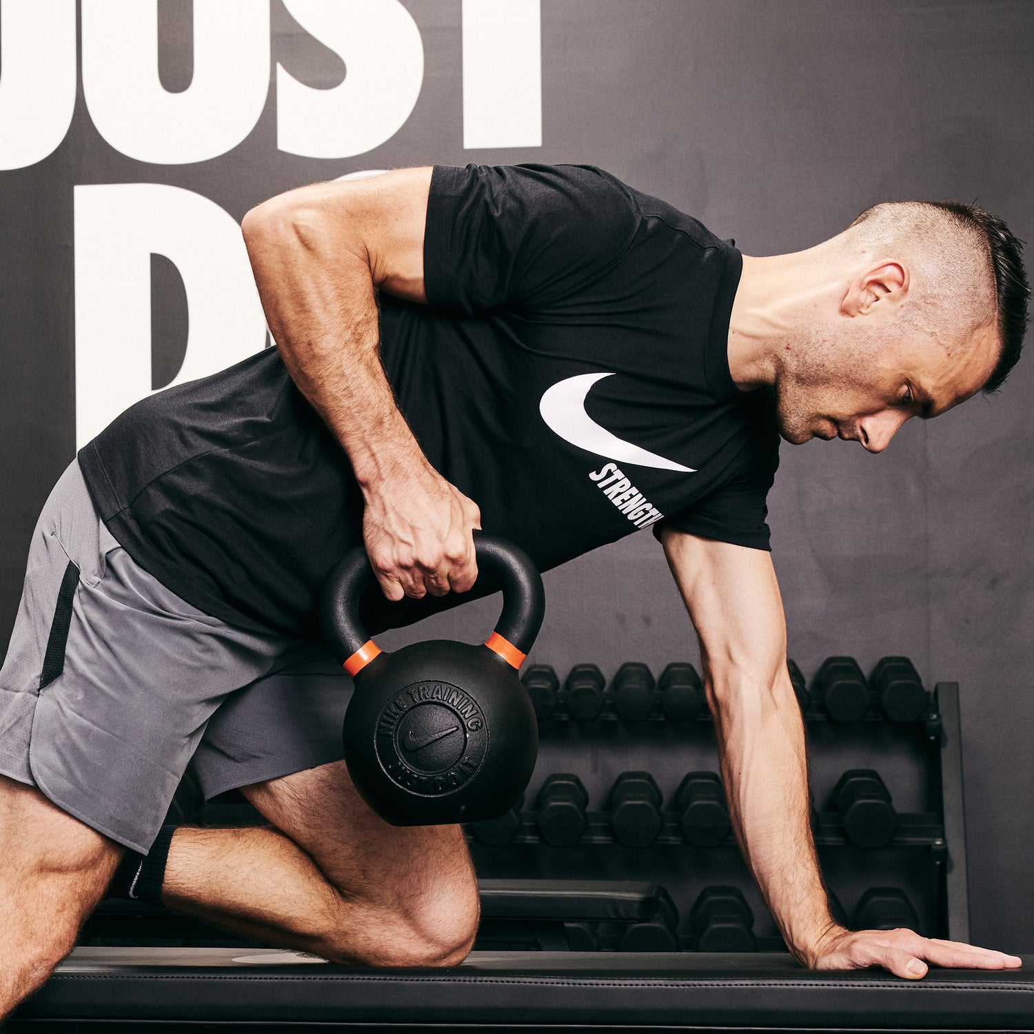 Male athlete rowing the Nike Kettlebell 62 LB using the Nike Roller Bench