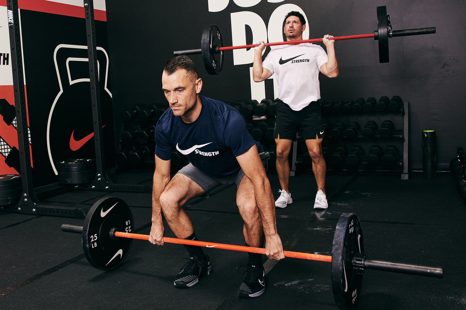 Two male athletes working out together. Lifting the Nike Coated Premium Barbell 20kg with Nike Rubber Bumper Plates