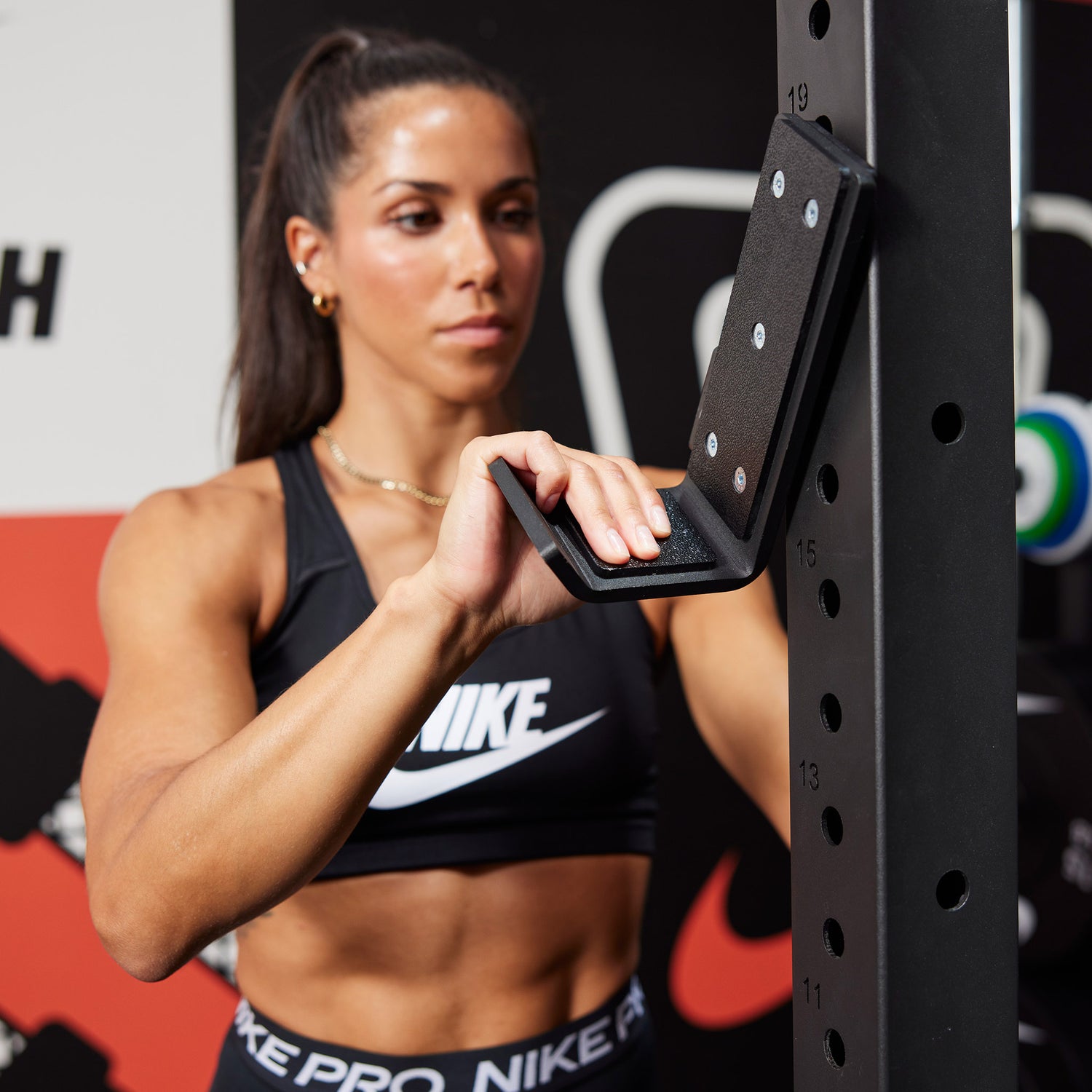 Female athlete attaching the J-cup to the Nike Squat Cage