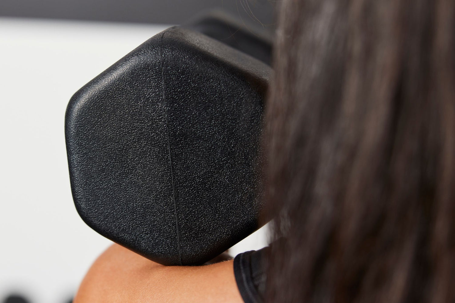 Athlete holding the Nike Dumbbell with sculpted edges on their bare shoulder