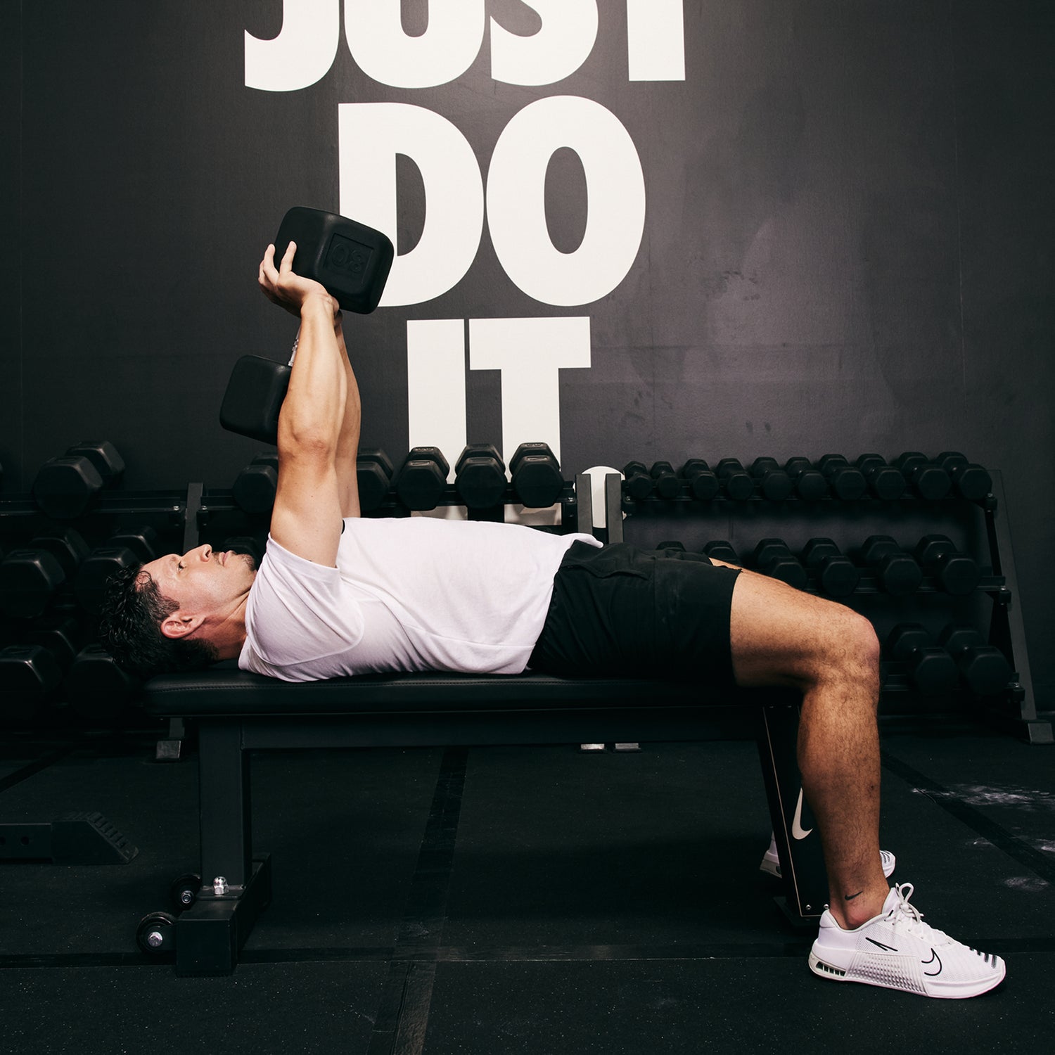 Male athlete lying on the Nike Rolling Weight Bench doing a tricep press with Nike Dumbbell