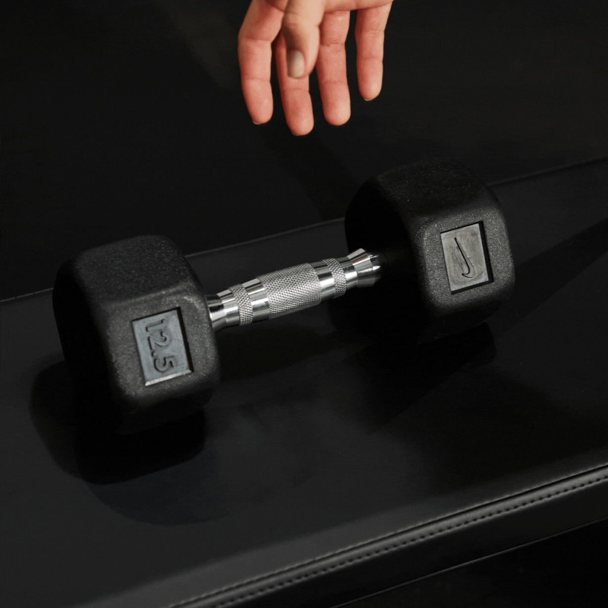 Athlete's hand grabbing the ergonomic handle of the Nike Dumbbell 12.5 LB