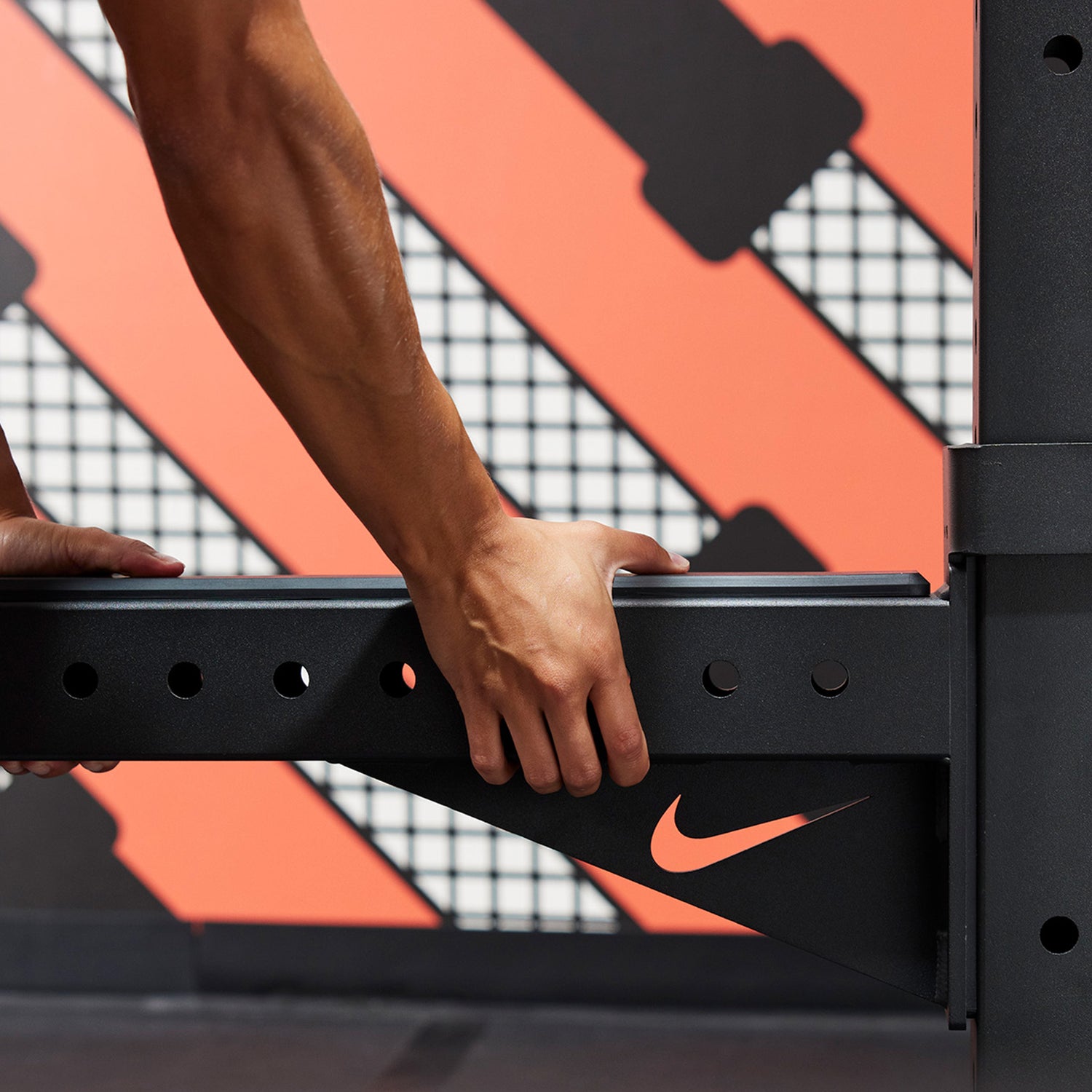 Athlete attaching the Nike Spotter Arm to the Nike Squat Cage