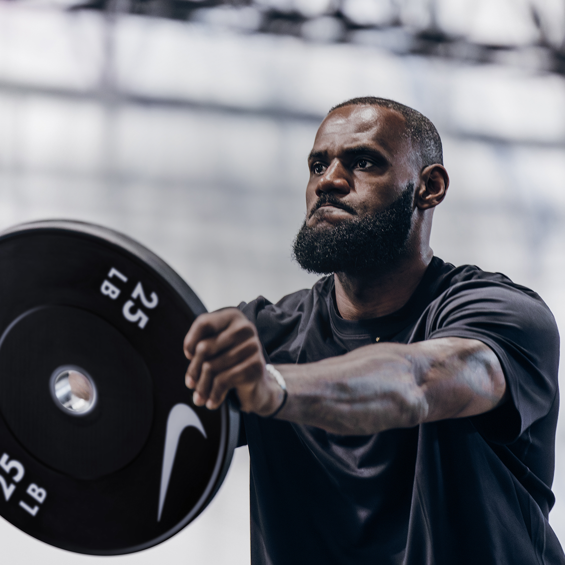 Man lifting a barbell with weights in a gym setting