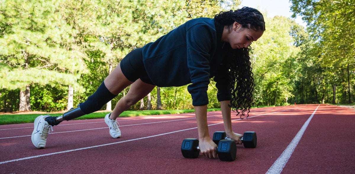 Paralympic adaptive athlete Beatriz Hatz in a plank position holding Nike Dumbbells