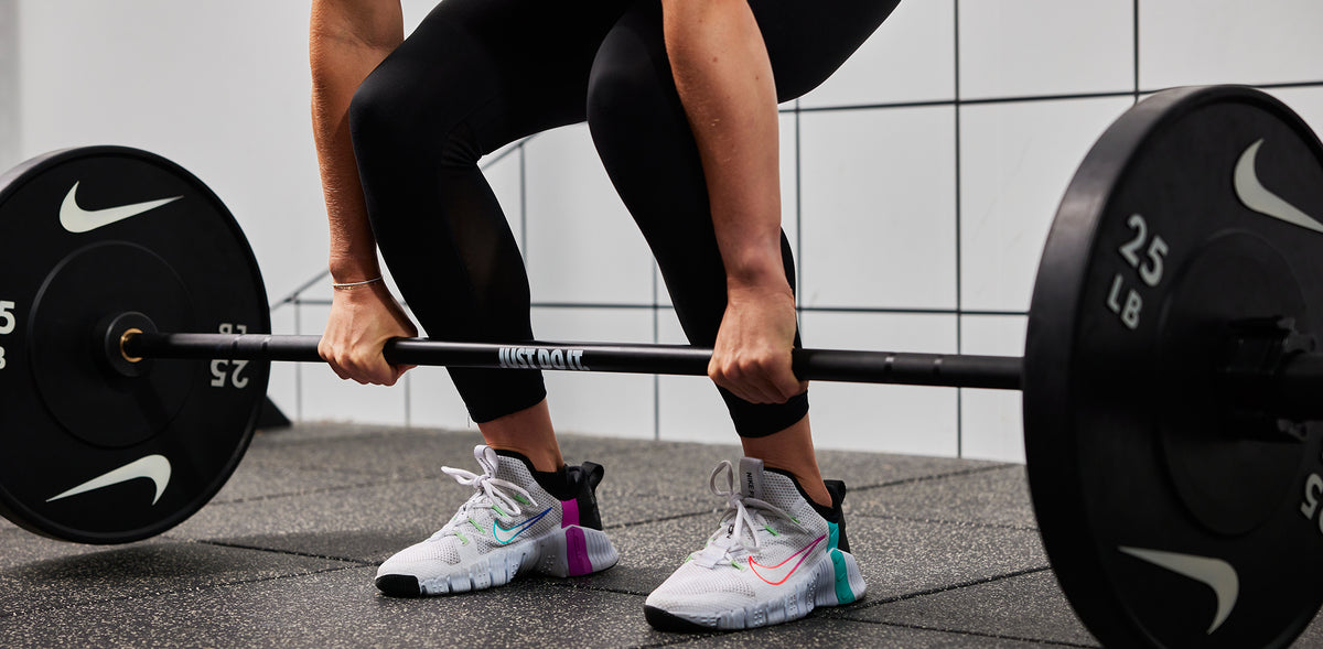 Athlete lifting the Nike coated Premium Barbell 15kg with Nike Rubber Bumper Plates 25 LB