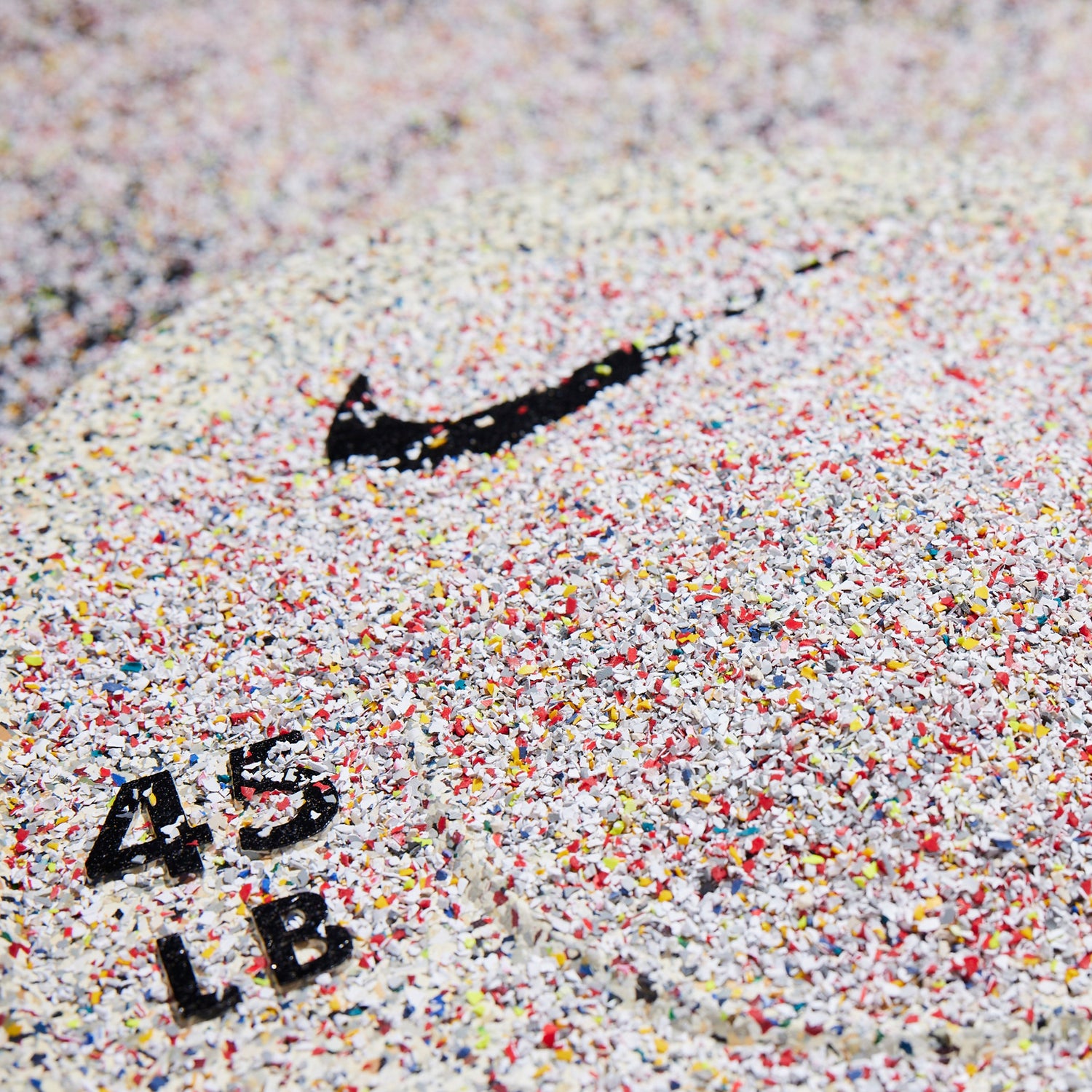 The Nike Rubber Bumper Plate (Grind) 45 LB plate shown with rubber scrap granules from Nike manufacturing