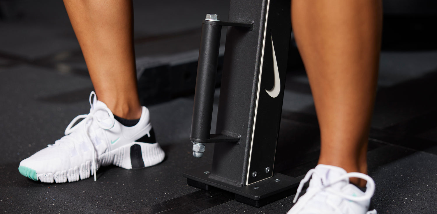 Athlete's feet straddling the single column for the Nike Rolling Weight Bench