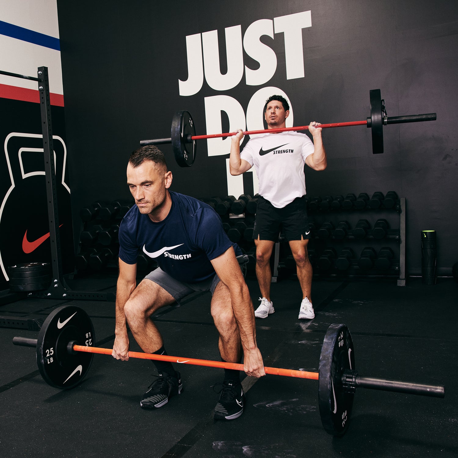 Two male athletes working out together. Lifting the Nike Coated Premium Barbell 20kg with Nike Rubber Bumper Plates