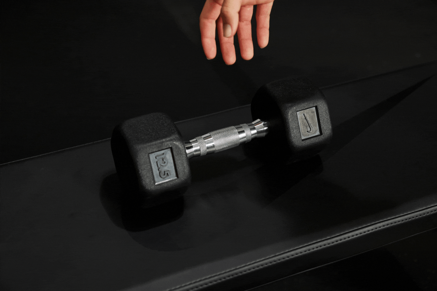 Athlete's hand grabbing the ergonomic handle of the Nike Dumbbell 12.5 LB