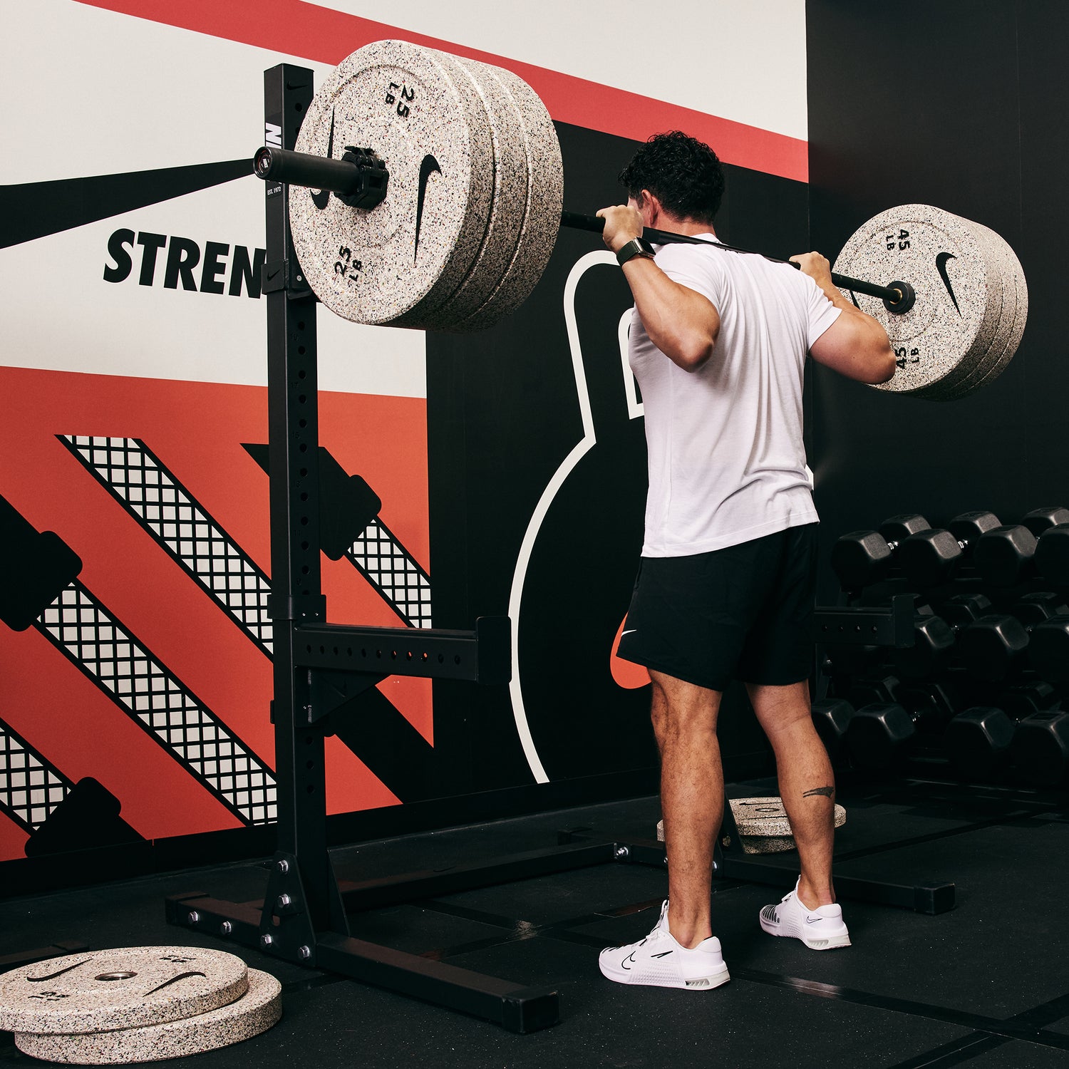 Male athlete squatting heavy with the Nike Barbell 20kg Black Chrome, Nike Rubber Bumper Plate (Grind), and the Nike Squat Stand
