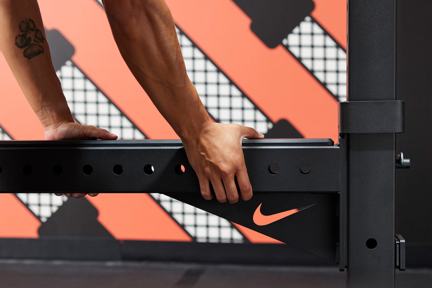 Athlete attaching the Nike Spotter Arms to the Nike Squat Stand