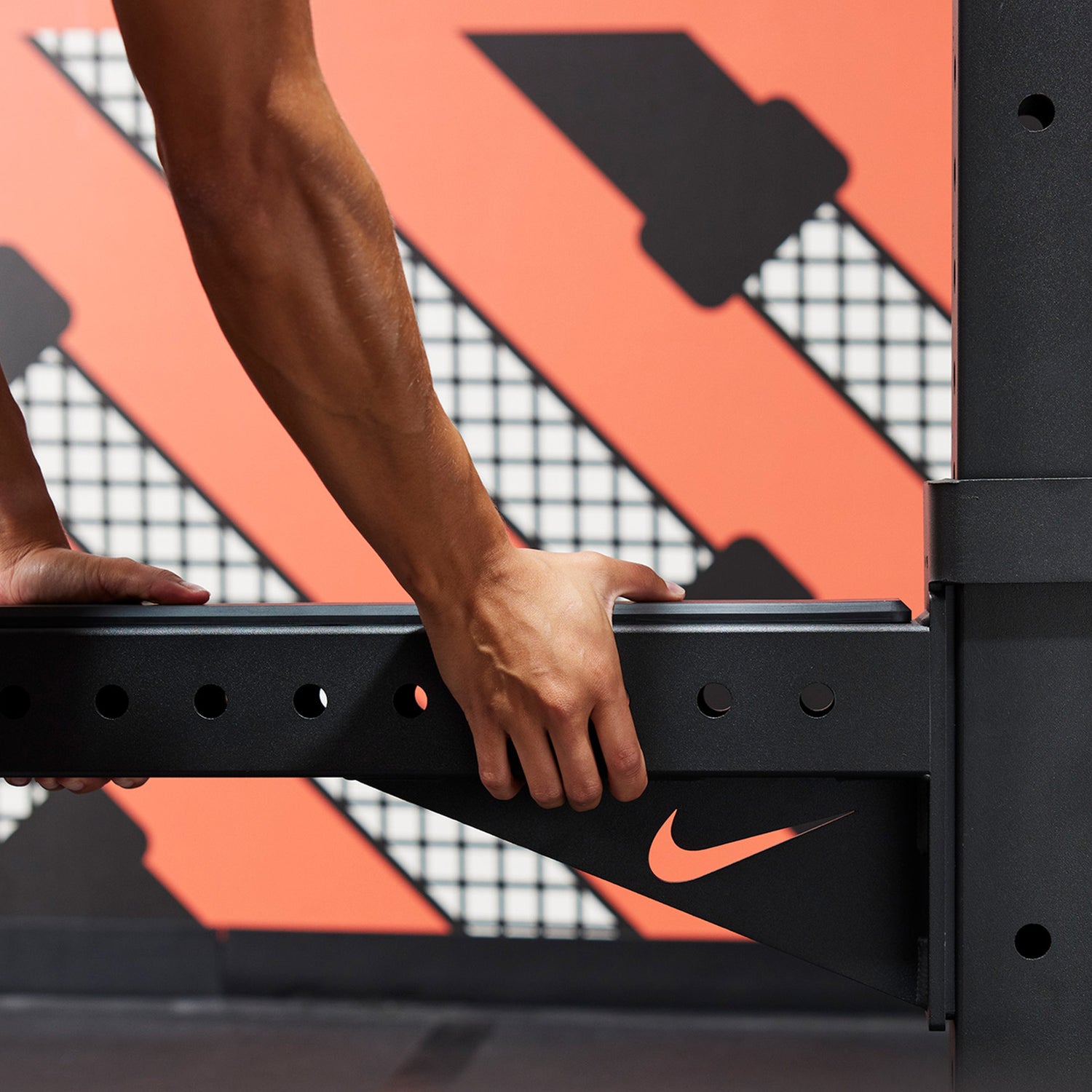 Athlete attaching the Nike Spotter Arms to the Nike Squat Stand