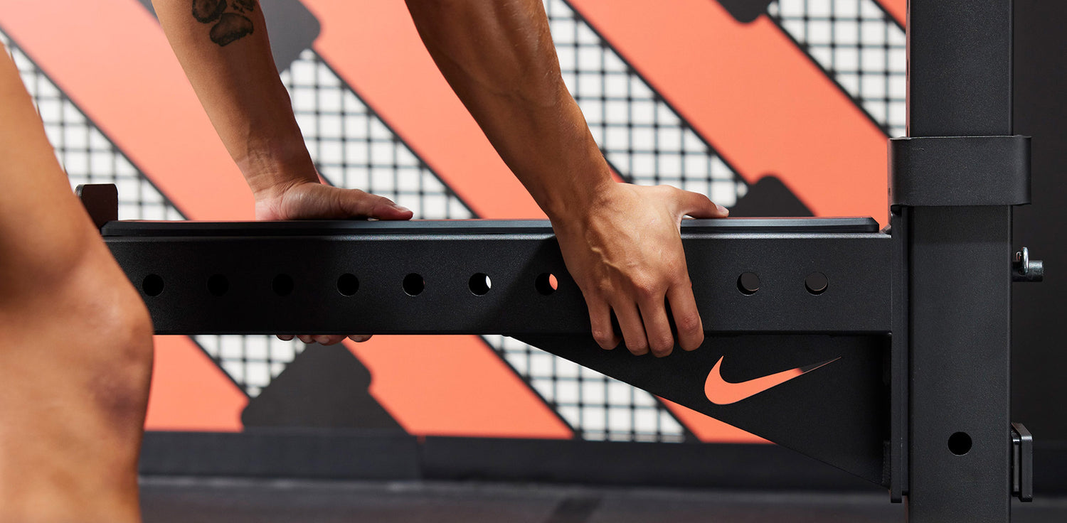 Athlete attaching the Nike Spotter Arm to the Nike Squat Cage